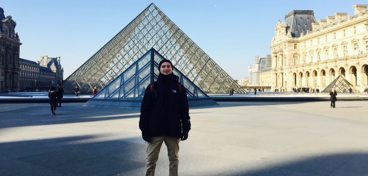 Image of a man in front of the Louvre glass pyramid